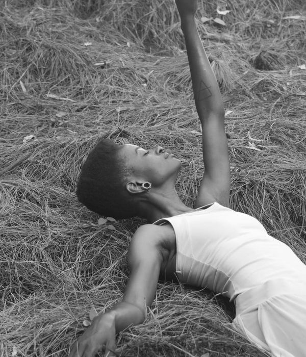 Woman in a relaxed pose with a serene expression in a minimalist setting.